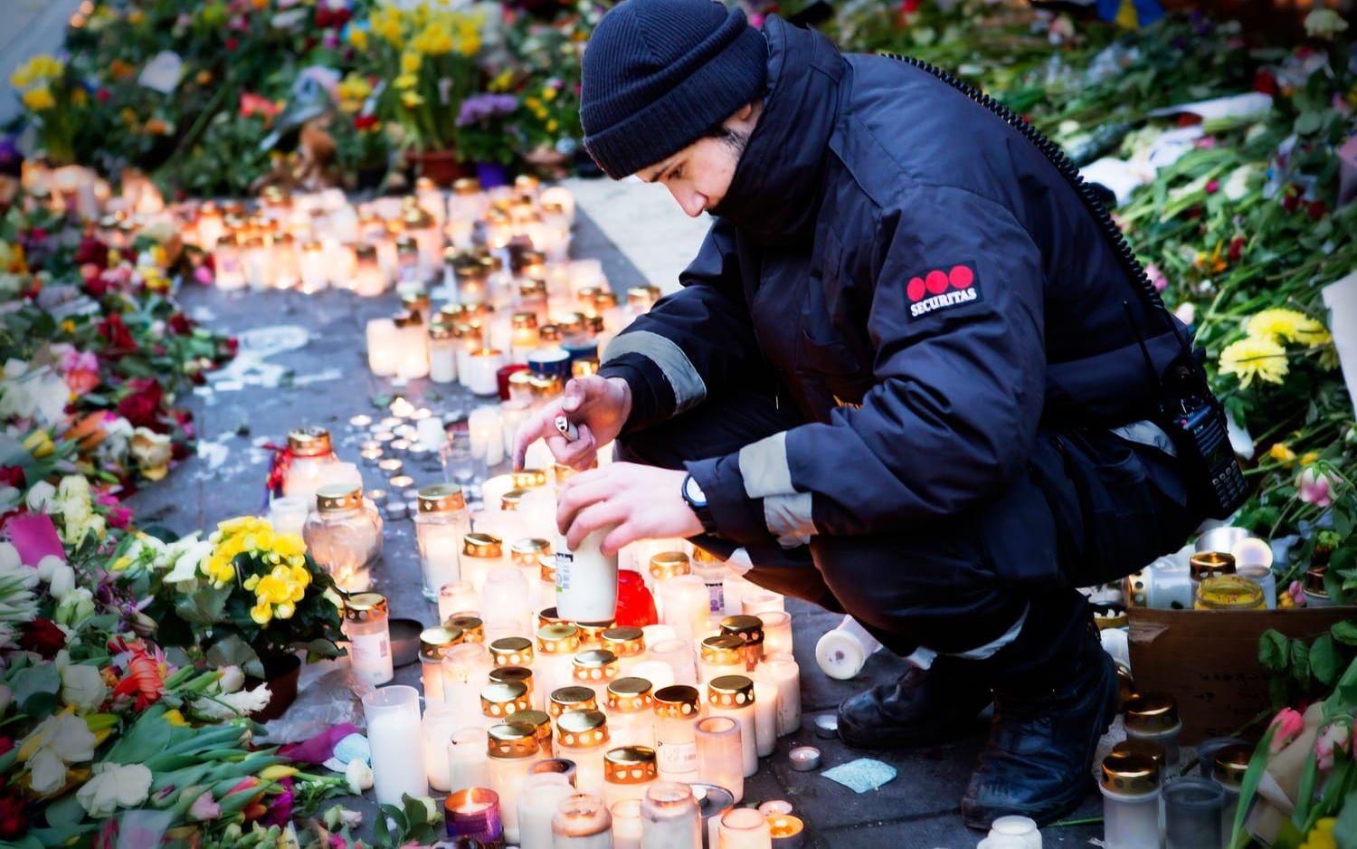 När lyktorna tänds. En vakt går runt bland gravljusen utanför Åhléns innan Stockholm vaknat. Foto: Caroline Tibell