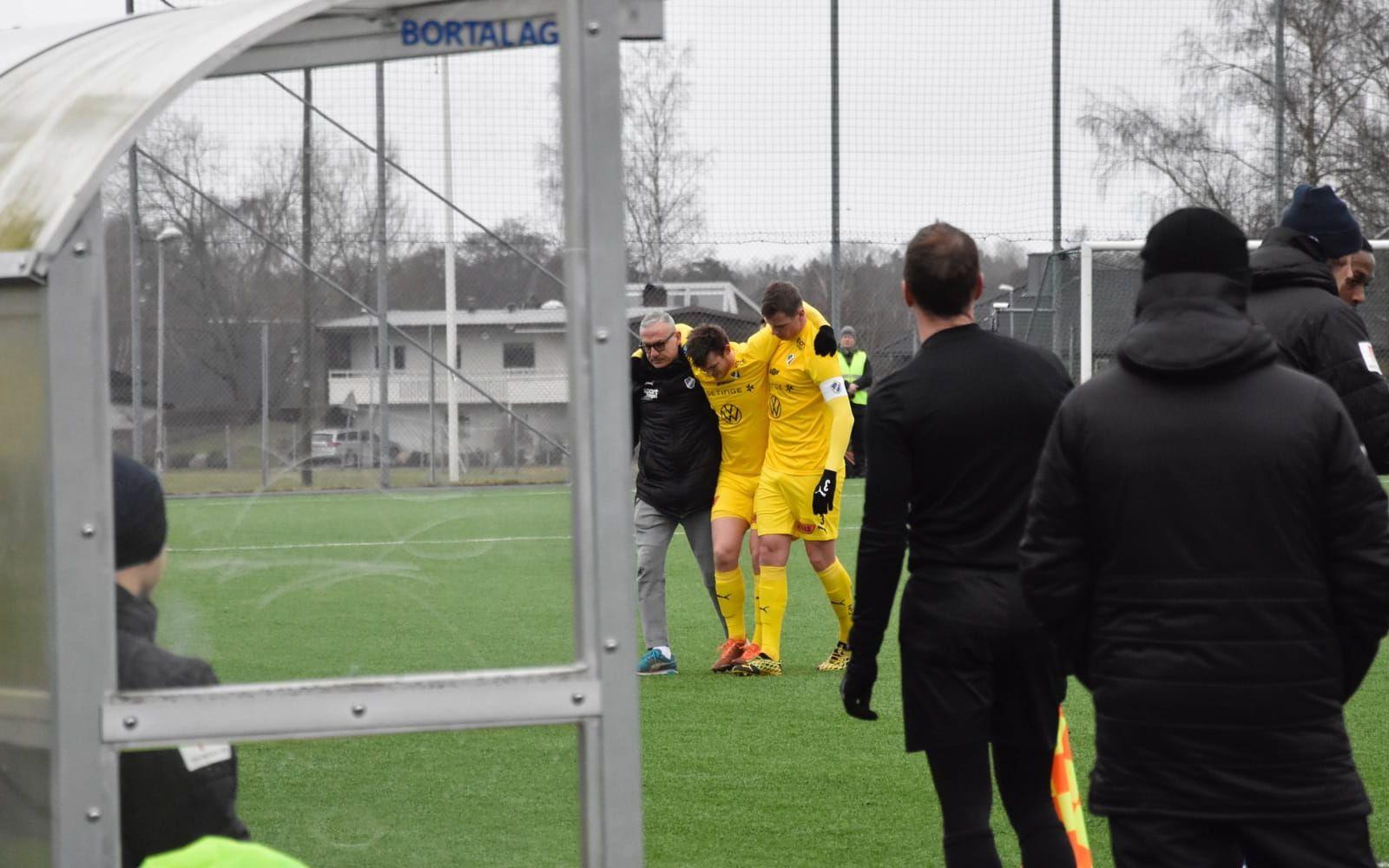 Knäskadade Jonathan Svedberg hjälps av planen av HBK:s sjukgymnast Simon Bakkioui och backen Alexander Berntsson.